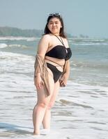 Portrait young asian woman fat chubby cute beautiful smile happy fun bikini swimwear body sexy front view tropical sea beach white sand clean and bluesky calm nature ocean wave water travel on holiday photo