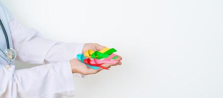 World cancer day, February 4. Doctor hold colorful ribbons, blue, yellow, red, green, white, pink and grey for supporting people living and illness. Health, Medical, awareness and Insurance concept photo