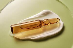 Ampoule in a drop of cosmetic cream on a green background. photo