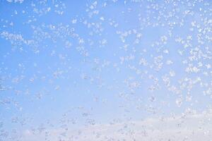 Abstract winter background. Frost on a frozen window against the blue sky. photo