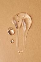 A drop of transparent cosmetic gel on a beige background. photo