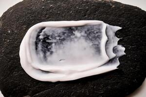 A smear of white cream on a black stone. photo