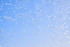 Abstract winter background. Frost on a frozen window against the blue sky. photo