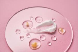 Gel, serum and a cream on a transparent round stand on a pink background. photo