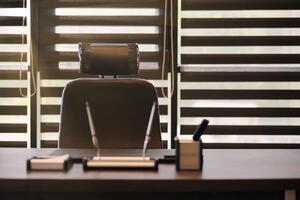 Business office workplace. Sunlight at work place for chief, boss or other employees. Table and comfortable chair. Light through the half open blinds photo