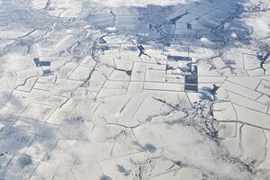 Aerial cloudscape view over clouds top to snow covered rivers, roads, cities and fields, winter air photo