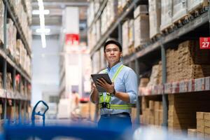 warehouse worker in a blue security suit uses a digital tablet to inspect inventory in a large warehouse. Distribution Center. Logistics and export of business. photo