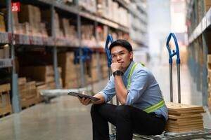 Asian warehouse worker who is tired from work. Being fired from work. Unemployed. Failed. Hopeless. Burned out at work. photo