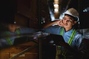 Stressed male manager or worker holding tablet and in warehouse A place to store ideas about workplace problems. Supply chain and warehousing concepts. photo