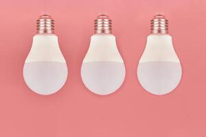 Three light bulbs, copy space. Energy saving minimal idea concept.Pink background. photo