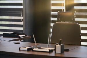 Business office workplace. Sunlight at work place for chief, boss or other employees. Table and comfortable chair. Light through the half open blinds photo