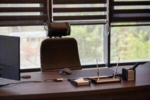 Business office workplace. Work place for chief, boss or other employees. Table and comfortable chair. Light through the half open blinds photo