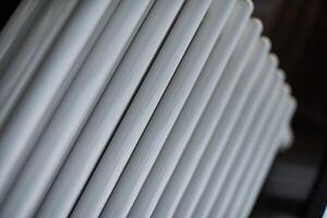 Heating radiator in office, close up. White heat exchangers. Iron aluminium steam radiator. Pipe pattern. photo