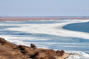 February seashore with melting ice near shore, seasonally nature landscape of coming spring photo