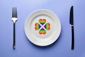 LGBT flag hearts in plate. Romantic gay dating in cafe or restaurant. Meeting new lgbt friends. photo