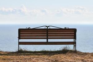 Empty bench on cliff before sea background, peaceful and quiet place for thinking alone photo
