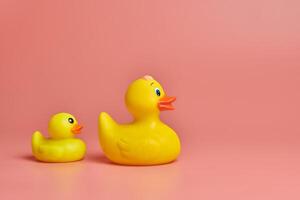 Two yellow rubber ducks toys, copy space. Cute funny bath toys, minimal kidult concept. Pink background. photo