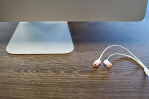 auriculares y monitor de computadora en el lugar de trabajo. trabajar con sonido o escuchar música en el trabajo. escuchar conversaciones telefónicas de negocios foto