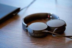 auriculares en la mesa de la oficina. auriculares conectados a la computadora portátil, copie el espacio. escuchando musica en el trabajo foto