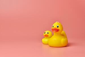 Two yellow rubber ducks toys, copy space. Cute funny bath toys, minimal kidult concept. Pink background. photo