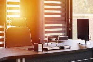 Business office workplace. Sunlight at work place for chief, boss or other employees. Table and comfortable chair. Light through the half open blinds photo