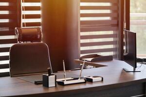 Business office workplace. Sunlight at work place for chief, boss or other employees. Table and comfortable chair. Light through the half open blinds photo