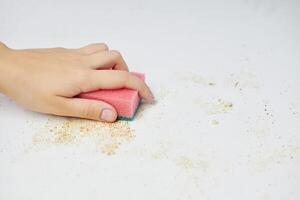 Sponge in woman hand removes dirt, bread crumbs and leftovers. Cleaning kitchen table. Household chores photo