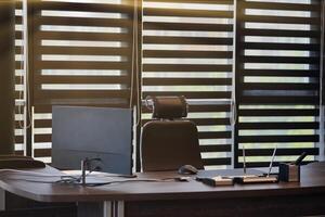 Business office workplace. Sunlight at work place for chief, boss or other employees. Table and comfortable chair. Light through the half open blinds photo