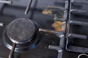 Unclean dirty kitchen black stove after soup boil over, dried food spots, fat stains dry food leftovers photo