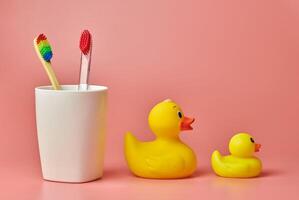 Two toothbrush and duck toy, copy space. Personal care tool for protect oral cavity, remove plaque and tartar. photo
