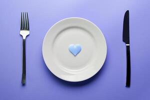 Waiting for a favorite dish in restaurant or cafe. Heart on plate with fork and knife. Lovers meeting at a daily lunch. photo