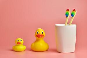 Two toothbrush and bathroom duck toys. LGBT personal care concept. Protect oral cavity, remove plaque and tartar. photo