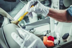 Automotive Worker Cleaning Car Dashboard Using a Soft Brush photo