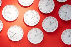 Many clock on red wall. clock concept. Time management concept with many clocks. photo