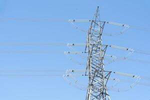 High electric tower isolated on blue sky background. A high voltage power pylons against blue sky. photo