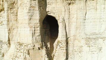 Relief white cliff slope with large hole or grotto near the top of slope. Shot. Mysterious cave in the cliff, close-up view video