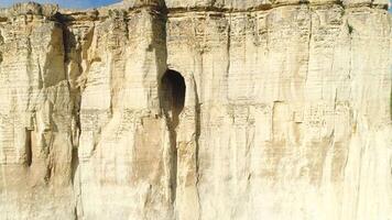 Linderung Weiß Cliff Steigung mit groß Loch oder Grotte in der Nähe von das oben von Neigung. Schuss. mysteriös Höhle im das Cliff, Nahansicht Aussicht video