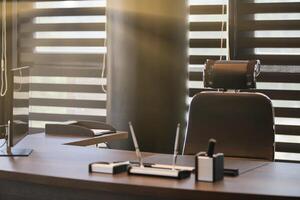 Business office workplace. Sunlight at work place for chief, boss or other employees. Table and comfortable chair. Light through the half open blinds photo