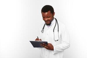 Black bearded doctor man in white coat with stethoscope filling medical records on clipboard photo