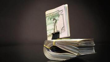 stack of dollar bills collected in an elastic band and a stationery clip, isolated on a black background. video