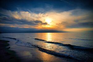 Sunset on the west beach on the Baltic Sea. Waves, beach, cloudy sky. Landscape photo