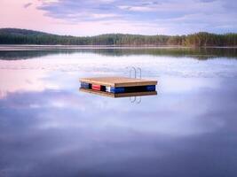 Swimming island in Sweden on a lake at sunset. Clouds reflected in the water. photo