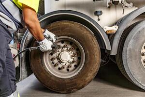 Crop mechanic tightening wheel of truck in workshop photo