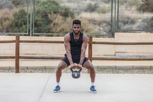 Muscular sportsman squatting with kettlebell photo