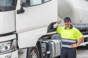 contento masculino conductor en uniforme sonriente mientras en pie por camión foto