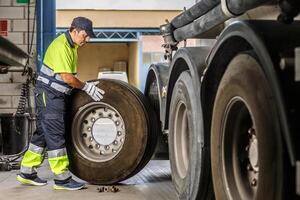 Male mechanic repairing truck wheel in workshop photo