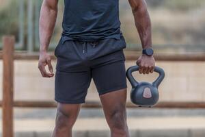 Faceless sportsman holding kettlebell in hand during workout photo