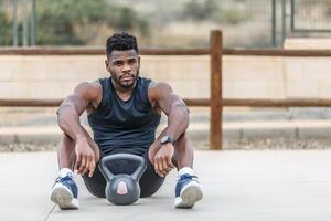 Serious African American man with kettlebell resting from workout photo