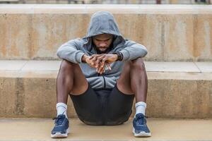 Depressed black sportsman sitting on ground photo