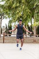 Strong black sportsman training with skipping rope photo